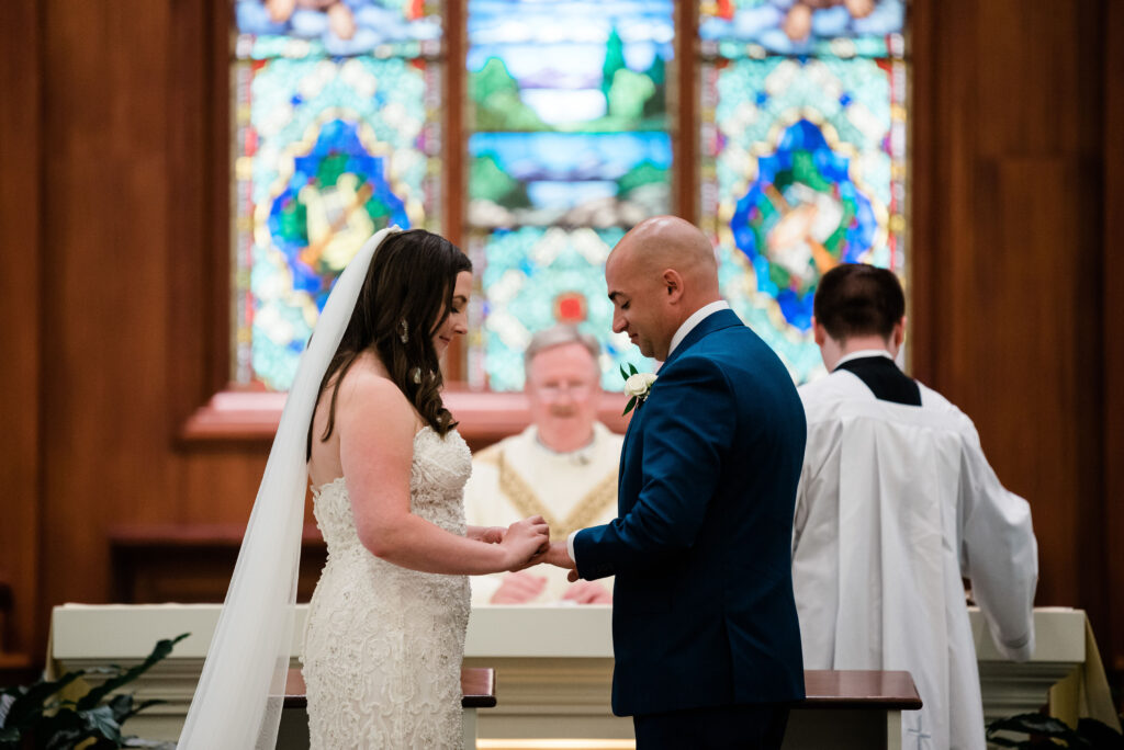 A couple exchanging rings at the altar during their ceremony. Officiant